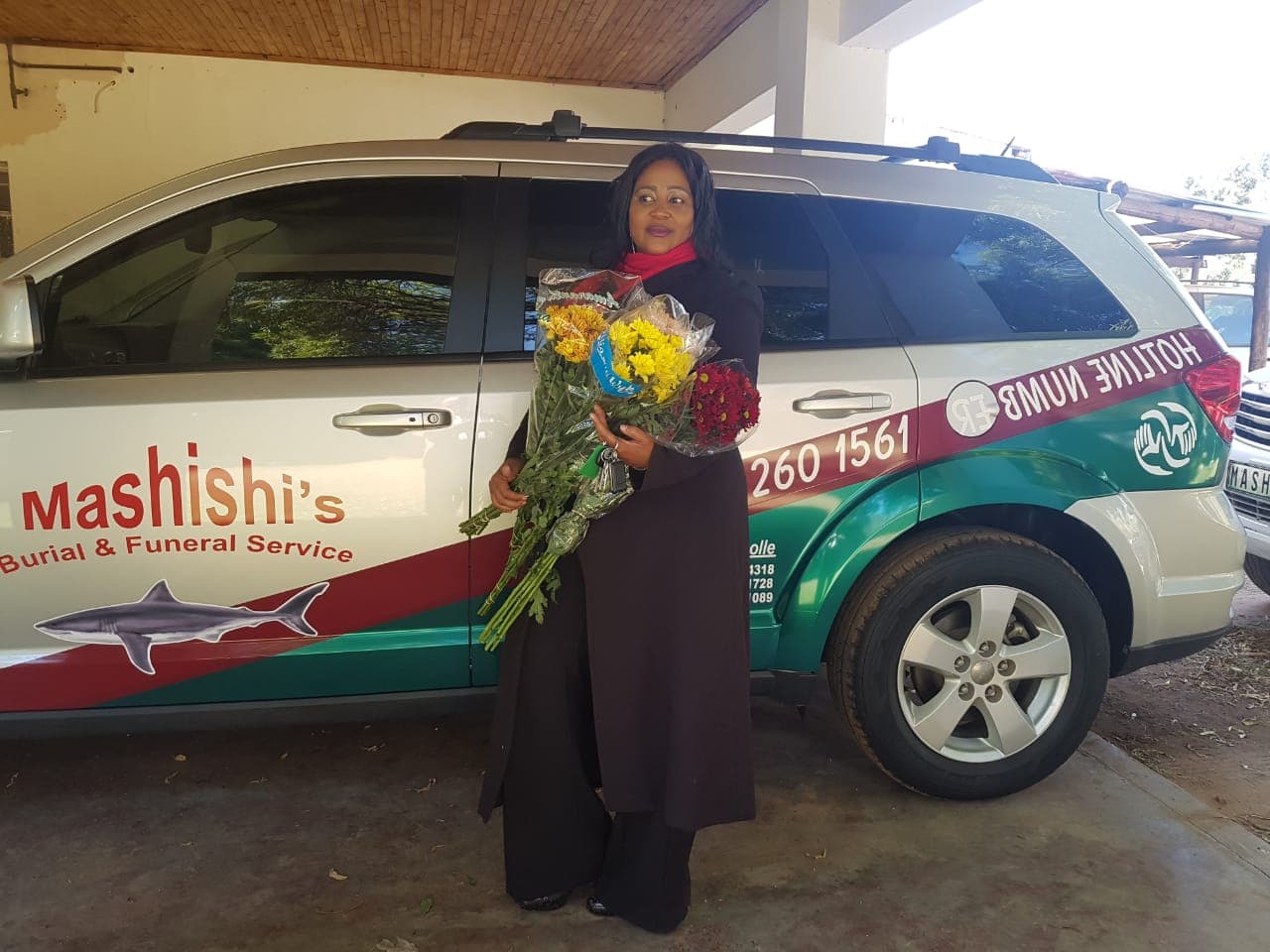 Mashishi team member beside a branded funeral vehicle